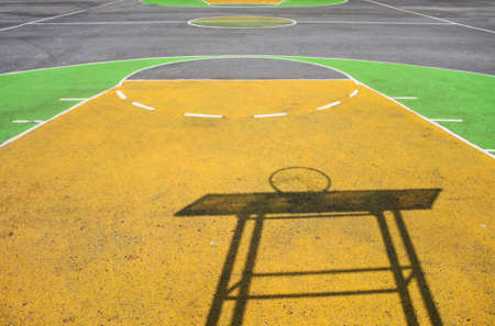outdoor playground basketball of asphalt and painted in yellow with green color and basketball board shadowの写真素材