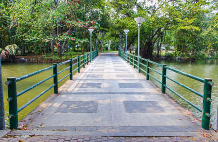 cement bridge over pond with metal handrails on parkの写真素材