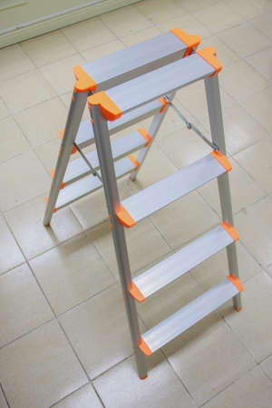 orange aluminum folding ladder, stepladder on tile floor for general repairの写真素材