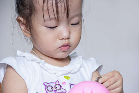 girl kid putting coin in piggy bank  mouth, money saving concept, focus eye