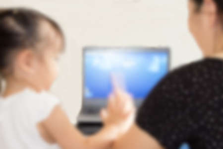Blurry mother and child watching a laptop at home, safety family technology conceptle Values)の写真素材