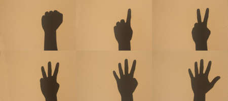 shadow hand sign of number, set on brown wallの写真素材