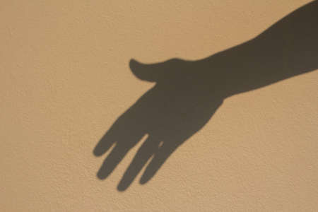 shadow helping hand concept on brown wallの写真素材