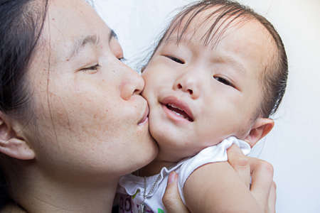 Asian mother kiss cry child at home