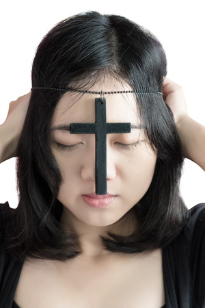 Beautiful asia woman with hopeful holding christian symbol of crucifix praying to God isolated on white background.の写真素材