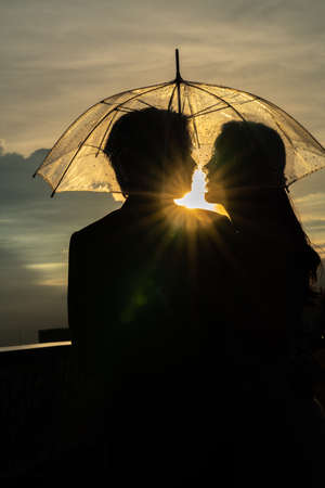 Silhouette couple prewedding under umbrella at sunsetの写真素材