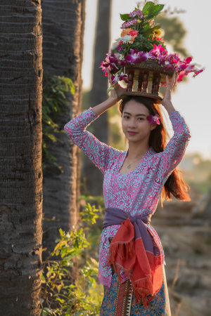 woman in bali costume Indonesian national dress walking in rice field in morningの写真素材