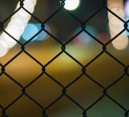 night light bokeh road behind grate on blur backgroundの写真素材