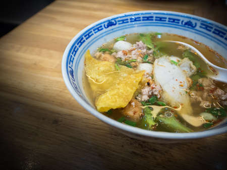 Spicy noodle  and Tom Yum  soup with red roast pork on wooden tableの写真素材