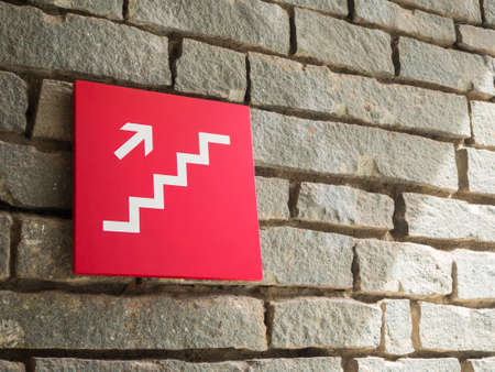 red stairs going up sign on wall brick backgroundの写真素材