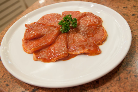 slided pork mixed with sauce on white dishの写真素材