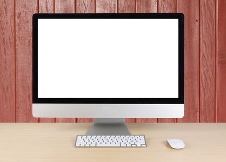 Modern computer, wireless keyboard and mouse on wooden table and red wood wall backgroundの写真素材