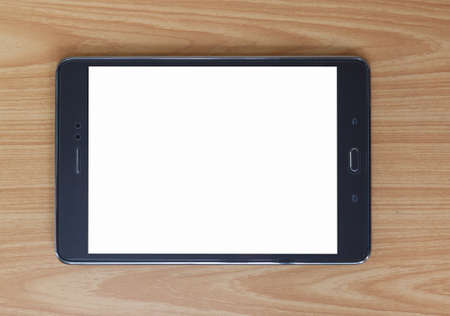 Top view of black tablet pc with white screen on wooden tableの写真素材
