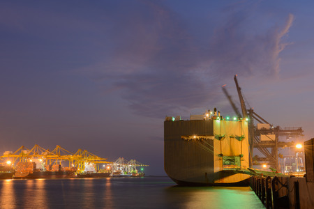 Large ship with operating crane at harbor night timeの写真素材