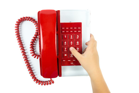 Child hand pressing number button on telephone