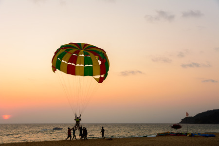 People enjoy parasailing at beach during sunset timeの写真素材