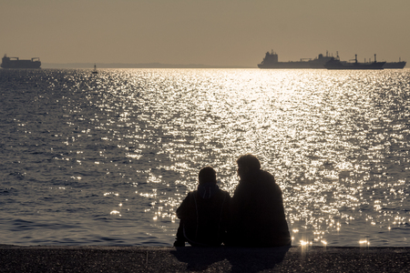 Two lovers looking at the Aegean Sea at sunset in Thessaloniki, Greeceの写真素材