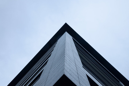 Corner of a skyscraper under a cloudy and cold sky seen from the bottomPicture of the corner of a...