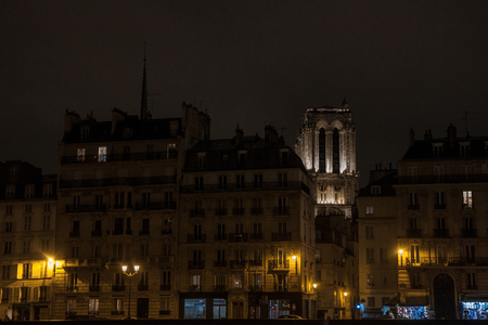 Our Lady of Paris cathedral surrounded by medieval residential buildings typical of Ile de la Cite in Paris, France, during an winter evening, taken from the quays of Seine Riverの写真素材