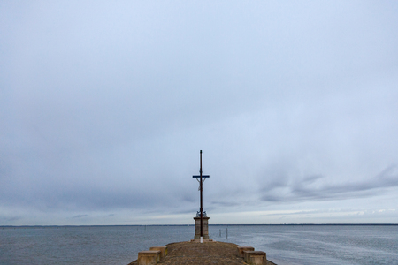 Sailors Cross during a cloudy rainy afternoon in Gujan Mestras, France, on Bassin d'Arcachon. It is a Christ Cross dedicated to the dead sailors who lost their lives on the Atlantic Oceanの写真素材