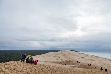 PILAT, FRANCE - DECEMBER 28, 2017: Tourists climbing the Pilat Dune (Dune du Pilat) during a cloudy afternoon. Pilat, or Pyla Dune is the biggest sand dune in Europe, located in Arcachon Bay, in AquitainePicture of people climbin the Pyla Sand dune duriのeditorial素材