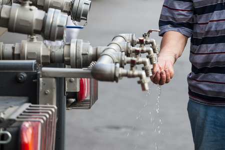 A man is washing his hands from the water tap with several pipes.