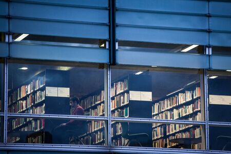MONTREAL, CANADA - NOVEMBER 6, 2018: Man reading on his laptop in one of the rooms of the Montreal Library, also called Bibliotheque et Archives nationales du Quebec, or Banq Grande Bibilothequeのeditorial素材