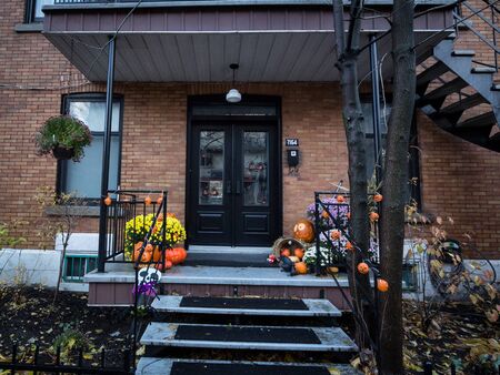 MONTREAL, CANADA - NOVEMBER 6, 2018: Typical North American front door of a suburban house decorated with Halloween decorations with the traditionnal carved pumpkins Picture of Halloween pumpkins on display in front of a suburban house of a north americのeditorial素材