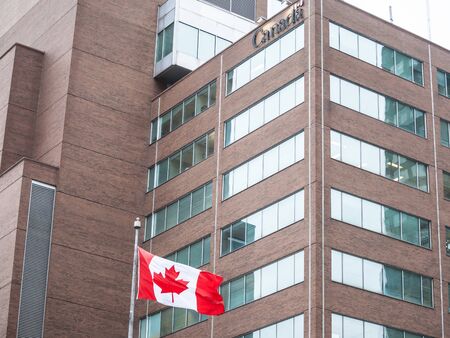 MONTREAL, CANADA - NOVEMBER 9, 2018: Canada Wordmark, the official logo of the Canadian government, on an administrative building next to a Canadian flag waiving in downtown Montreal, Quebec

Picture of the flag of Canada on a government building, with thのeditorial素材
