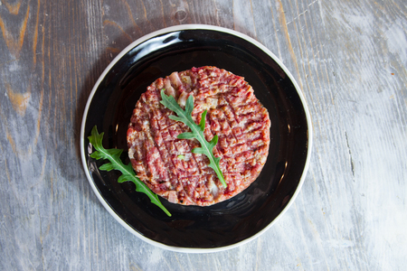 Steak tartare, cut and sliced with a knife, made of ground minced beef, on display on a rustic wooden table.の写真素材