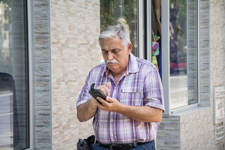 BELGRADE, SERBIA - JULY 14, 2015:  old senior white man standing and looking confused at smartphone, to use its internet mobile services

Picture of one man, senior white male caucasian, looking confused at a mobile phoneのeditorial素材