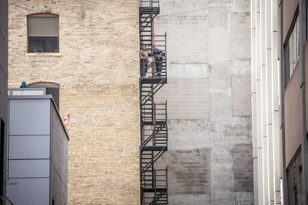 TORONTO, CANADA - NOVEMBER 14, 2018: Construction workers fixing Fire escape rusty stairs and ladders, in metal, on a typical North American old brick building. These stairs, made for emergency, are symbolic of the architecture

picture of vintage fire esのeditorial素材