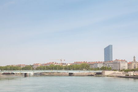 Pont de la Guillotiere bridge in Lyon, France over a panorama of the riverbank of the Rhone river (Quais de Rhone) with older buildings and a modern skyline in backgroundの写真素材