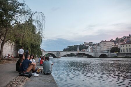 LYON, FRANCE - JULY 17, 2019: French people, mainly young men and women sitting on the riverbank of the Saone (quais) in the evening while people are gathering for the tradition of apero

Picture of people sitting on the quays of the riverbank of the Saonのeditorial素材