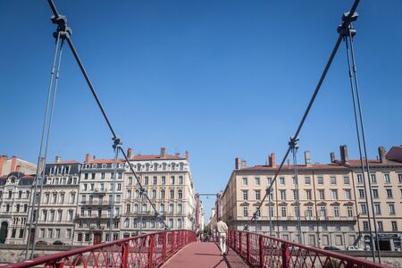 LYON, FRANCE - JULY 19, 2019: Man walking on the Pont Saint Georges bridge in Lyon, facing old...