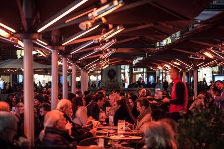 VIENNA, AUSTRIA - NOVEMBER 6, 2019: Crowd of people sitting at the terrace of a Vienna Bar Cafe, being heated for winter with an electric heating producing a red light.

Picture of the terrace of a bar cafe and restaurant of Vienna, Austria, crowded and pのeditorial素材