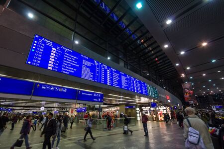 VIENNA, AUSTRIA - OCTOBER 30, 2019: Departures board of Wien Hauptbahnhof with passengers rushing and waiting to take their trains in the main railway station of Vienna.Picture of passengers rushing out of the main entrance to Wien Haupfbahnhof train stのeditorial素材