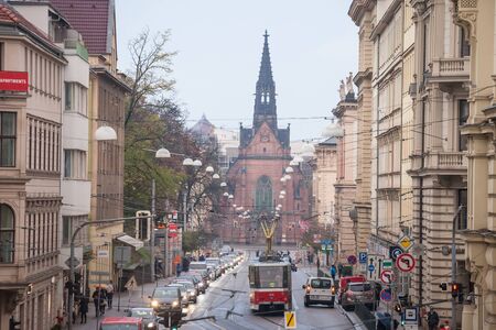 BRNO, CZECHIA - NOVEMBER 5, 2019: Jan Amos Comenius Church, or chram jana amose komenskeho, or red church, seen from Husova street with traffic jams, cars rushing and trams passing by.

Picture of a panorama of Husova street in Brno, Czech republic, packeのeditorial素材