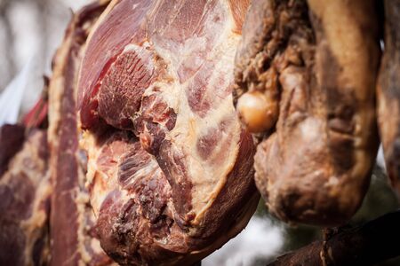 Serbian ham, called prsut, italian style, similar to prosciutto crudo, hanging in the countryside of Serbia. Prosciutto is a typical dry cured meat of pork produced in Italy, Spain and in the Balkans.Picture of a Serbian Prsut Ham drying on a rod in the countryside of Serbia. It is similar to the Italian Prosciutto Crudo, is an Italian dry-cured ham that is usually thinly sliced and served uncooked; this style is called prosciutto crudo in Italianの写真素材