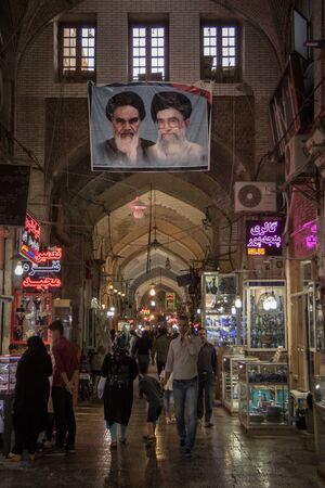 ISFAHAN, IRAN - AUGUST 8, 2018: Street of the Isfahan bazar ith the portraits of the 2 Supreme leaders of the Islamic Republic of Iran, Ali Khamenei & Ruhollah Khomeini hung on the roof.Picture of the covered bazar of Isfahan, Iran, with a huge propaganのeditorial素材