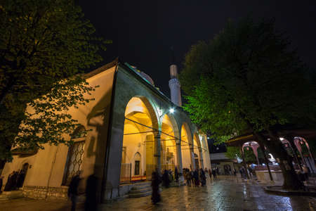 SARAJEVO, BOSNIA HERZEGOVINA - APRIL 15, 2017: People praying in front of Gazi Husrev Begova mosque in Sarajevo. The mosque is the main landmark of the ottoman part of the capital city of Bosnia.

Picture of Gazi Husrev Bey mosque at night with people praのeditorial素材