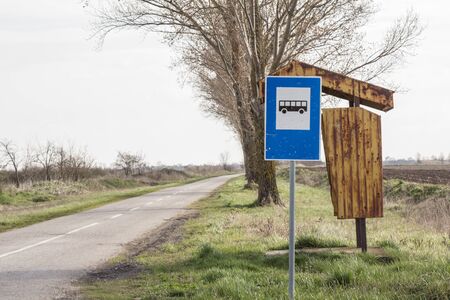 Abandoned bus stop Yugoslav design, in front of a neglected countryside landscape and a damaged road in Serbia, in a rural area hit by emigration.

Picture of a metal bus stop, of Yugoslav conception, abandoned and rusted, in the countryside of Serbia, facing an old road and a neglected agricultural field.の写真素材