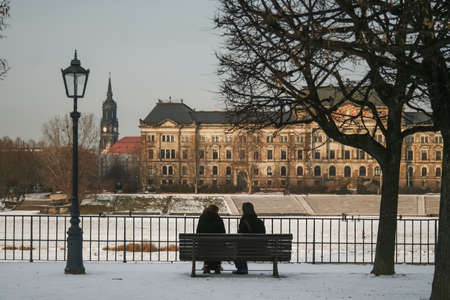 DRESDEN, GERMANY - DECEMBER 8, 2012: To persons, lovers, sitting on Terrassenufer, the Elbe riverbank of the city, in winter, during a cold sunset, with snow.

Picture of two persons sitting in front of the Elbe river on terrassenufer in the downtown of Dのeditorial素材