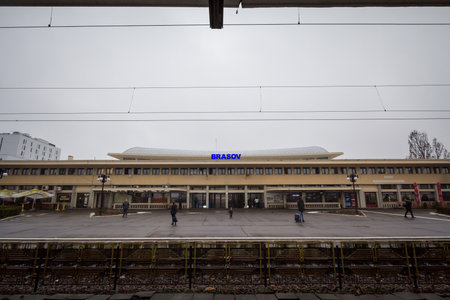 BRASOV, ROMANIA - FEBRUARY 15, 2020: Brasov train station (Gara de Brasov) seen from its main platform with passengers waiting for an intercity train during a cloudy morning.のeditorial素材