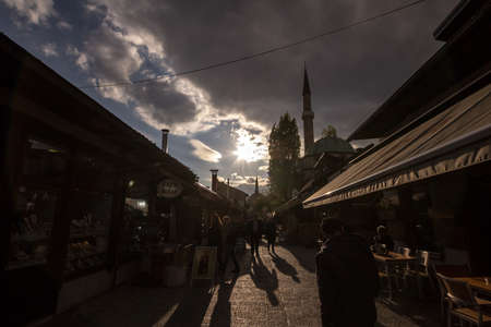 SARAJEVO, BOSNIA AND HERZEGOVINA - APRIL 17, 2017: Street with tourists and a Mosque Minaret in the Bascarsija district. Bascarsija is a symbol of Sarajevo, with its oriental architecture.のeditorial素材