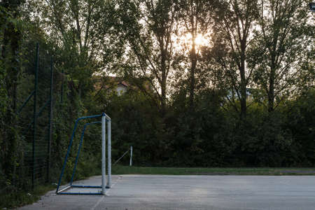 Soccer goal with its football net on display on a small asphalted playground used as a soccer field in an urban environment at dusk.の写真素材