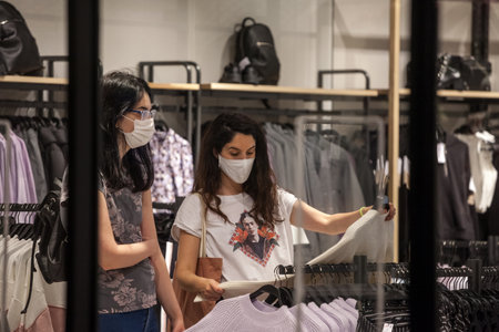BELGRADE, SERBIA - SEPTEMBER 25, 2020: Clients, women, looking at tshirts in a fashion retailer...