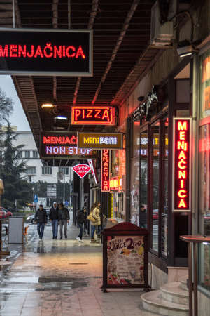 NOVI SAD, SERBIA - MARCH 13, 2016: Neon and led lights for restaurants, fast food, and pizzerias with their red tint in the city center of Novi Sad, a hotspot for snacking. Picture of a street in Novi Sad, Serbia, with the lights, neon and led, indicatingのeditorial素材