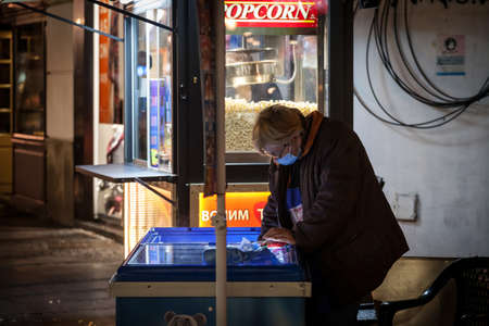 BELGRADE, SERBIA - OCTOBER 10, 2020: Female Senior Worker, ice cream seller, serving ice cream in the streets of Belgrade.のeditorial素材