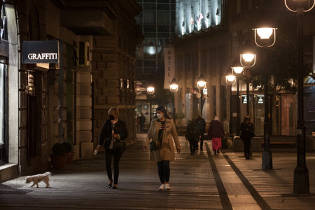 BELGRADE, SERBIA - OCTOBER 30 2020: Women, middle aged white caucasian females, walking a dog on a leash wearing face mask breathing protective equipment.のeditorial素材